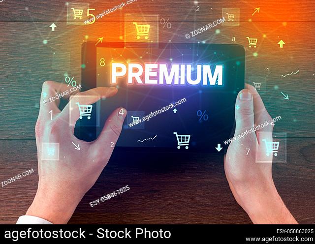 Close-up of a hand holding tablet with PREMIUM inscription, online shopping concept
