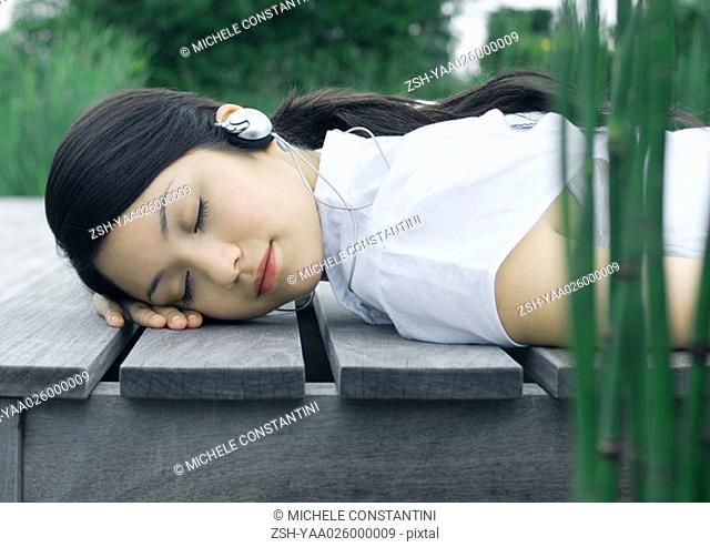Woman lying on deck, listening to headphones