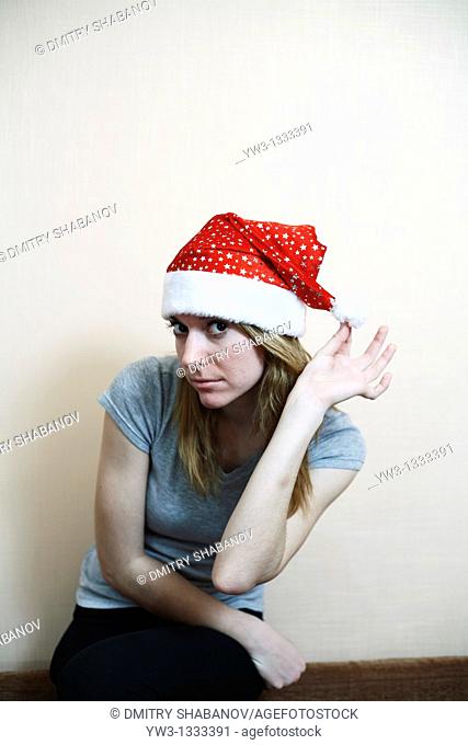 pretty girl in the Christmas hat against light wall posing