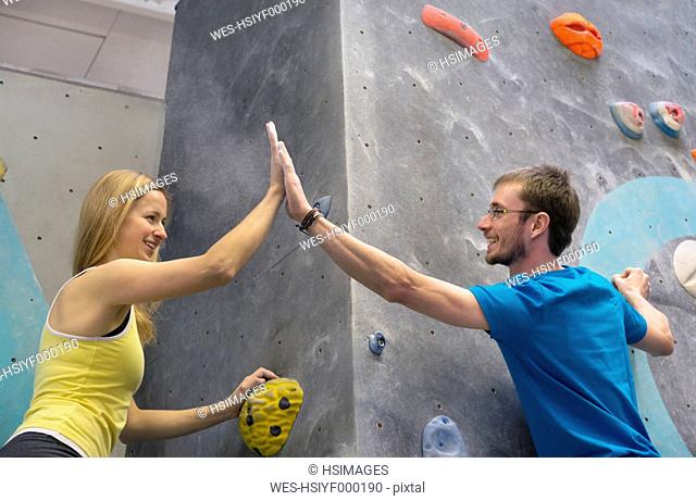 Germany, Bavaria, Munich, Young man and woman giving high five at top, smiling