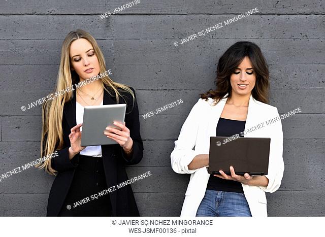 Two businesswomen using tablet and laptop