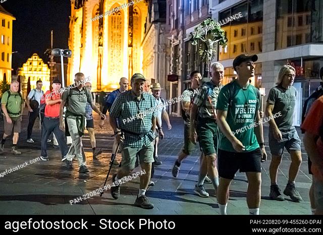 20 August 2022, Bavaria, Würzburg: Pilgrims walk through the city center of Würzburg. The Lady Chapel can be seen in the background