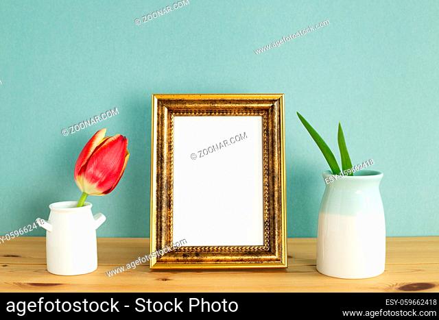 Home interior. Photo frame with red tulip on wooden table with mint green background. floral arrangement, copy space