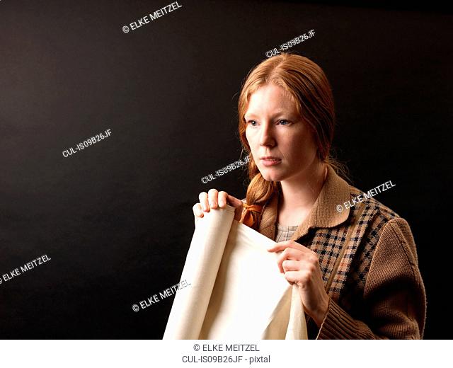 Portrait of young female designer holding rolled fabric