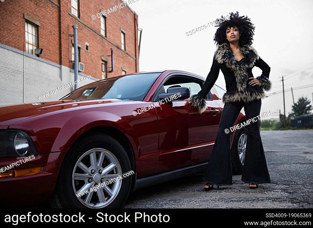 Full length tough portrait of a young African American woman with her car