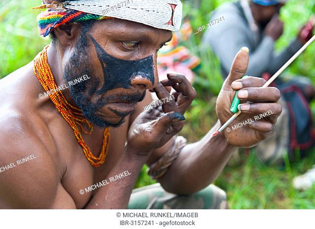 Man applying make-up for the traditional Sing Sing gathering in the highlands