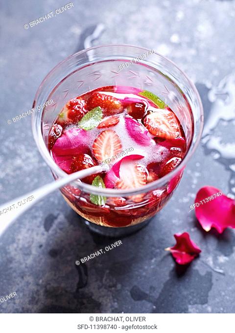 A glass of strawberry punch with rose petals