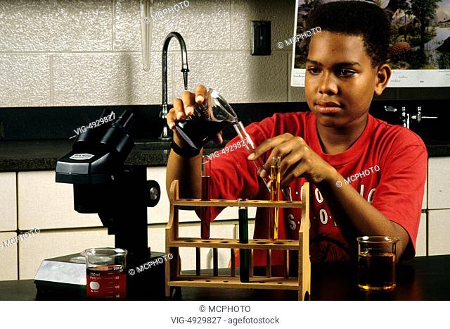 Black boy student age 13 in Eighth grade learning science at lab desk - 01/01/2014