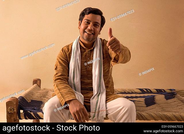 A RURAL MAN HAPPILY SHOWING THUMBS UP IN FRONT OF CAMERA