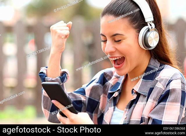 Excited teen with headphones checking smart phone