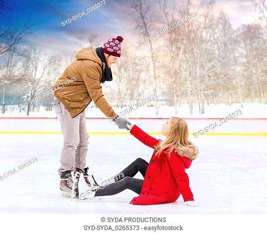 man helping woman to get up from skating rink