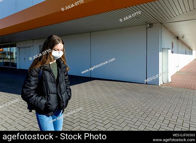 Girl with mask walking outside at closed shopping center