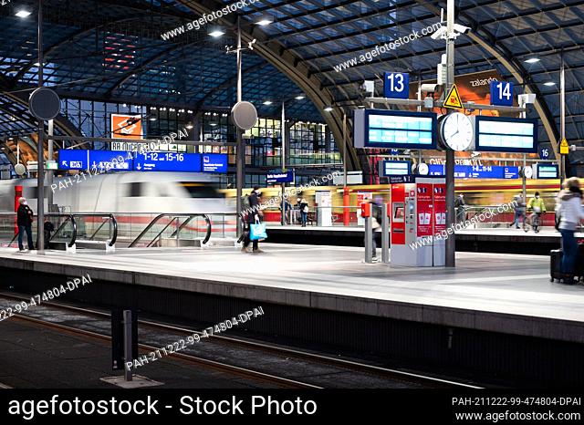 22 December 2021, Berlin: Rail passengers stand on the platform at Berlin Central Station at Christmas time while a train arrives