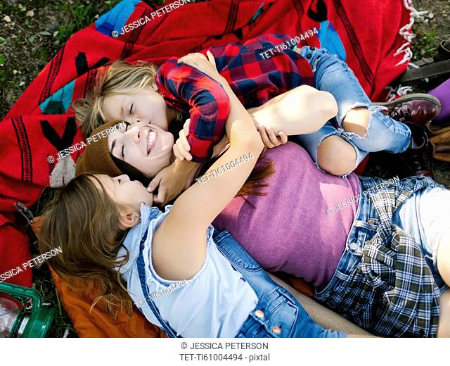 Woman with son (6-7) and daughter (8-9) lying on blanket