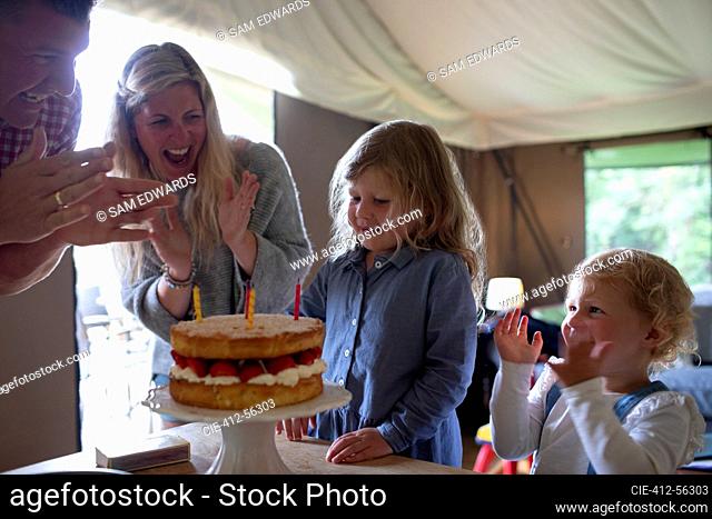 Happy family celebrating birthday with strawberry cake