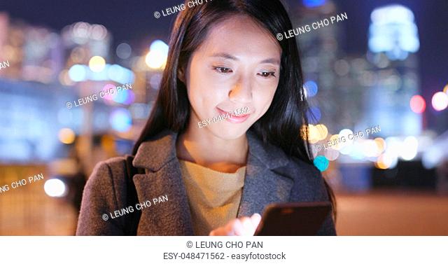 Woman look at mobile phone in city at night