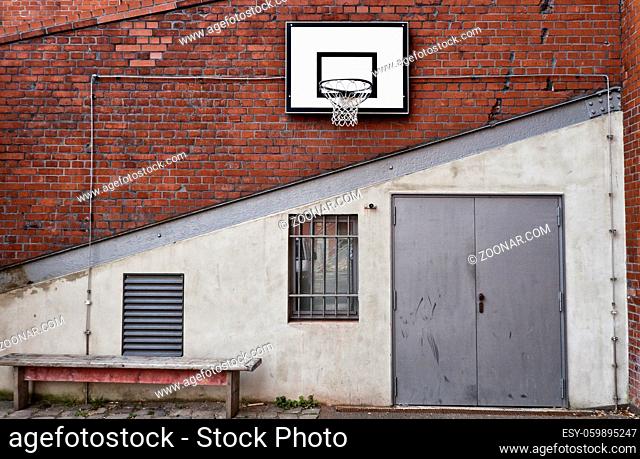 Basketballkorb an einer roten Steinmauer