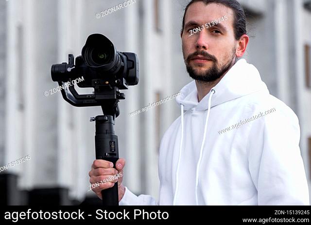 Young Professional videographer holding professional camera on 3-axis gimbal stabilizer. Pro equipment helps to make high quality video without shaking