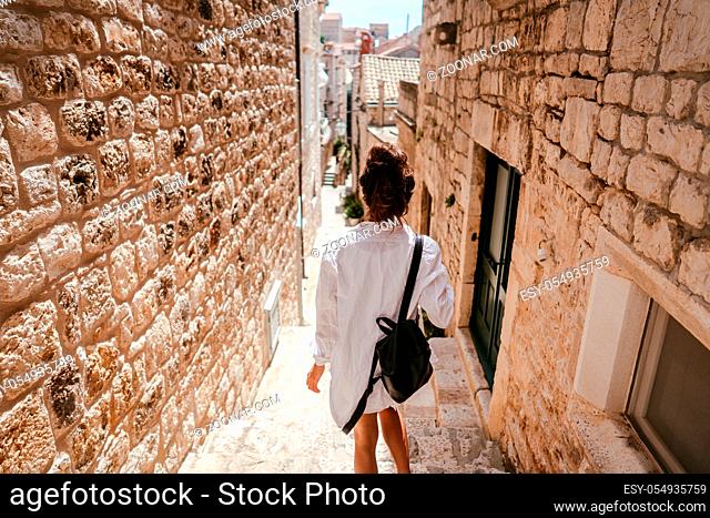 Young girl walking through ancient narrow streets on a beautiful summer day in Croatia south Europe