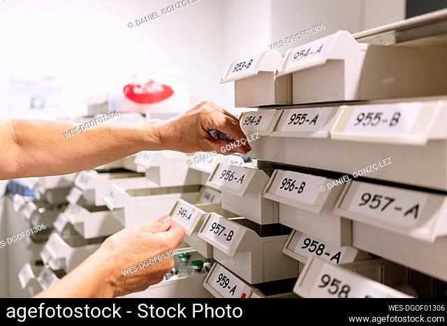 Hands of female worker placing medicines in trays at pharmacy