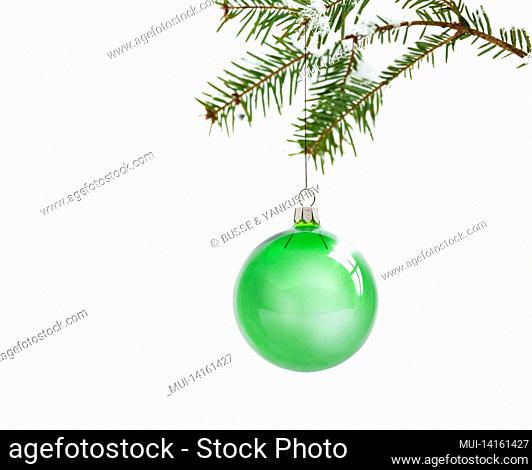 green christmas balls on a snow-covered pine branch