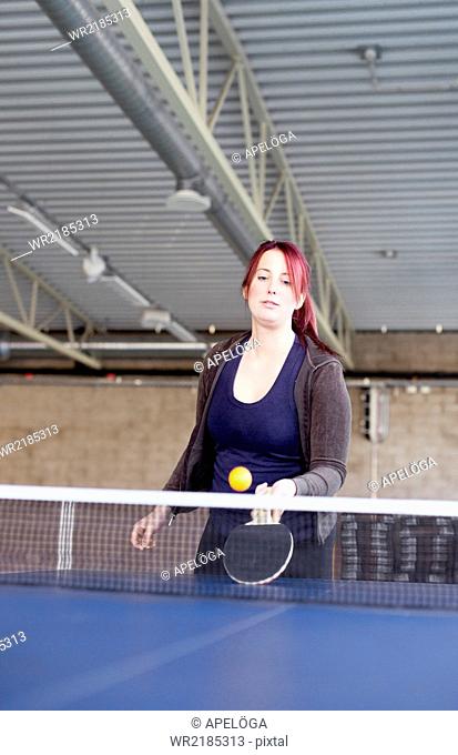 Young woman playing table tennis in fitness club