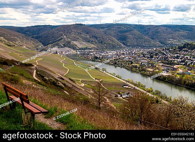 Panoramic view on the valley of the river Moselle and the city Bernkastel-Kues with a brown bench in the foregrouind