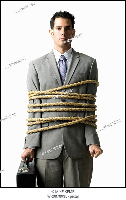 businessman in a full suit tied up with a rope around his mid section
