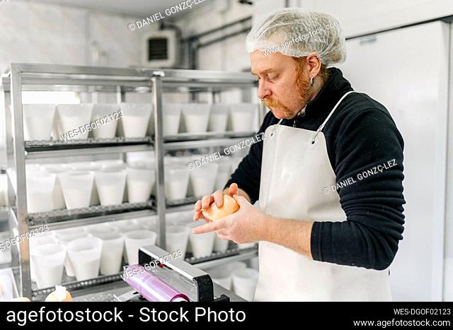 Male chef wearing apron checking cheese at storage room