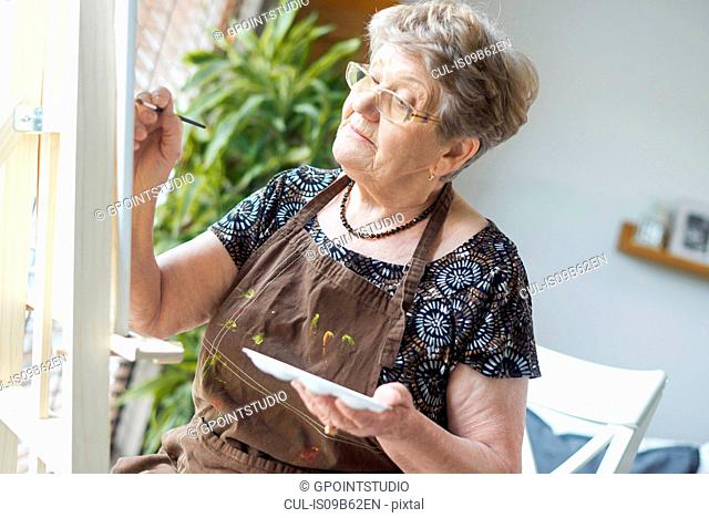 Senior adult woman painting on easel