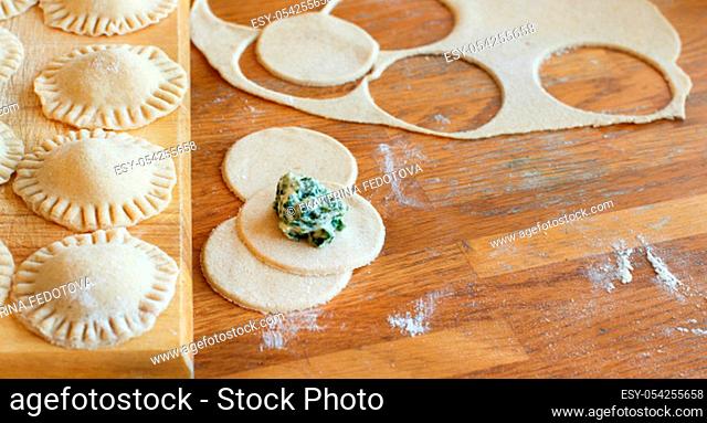 Making ravioli with ricotta cheese and spinach on a wooden board
