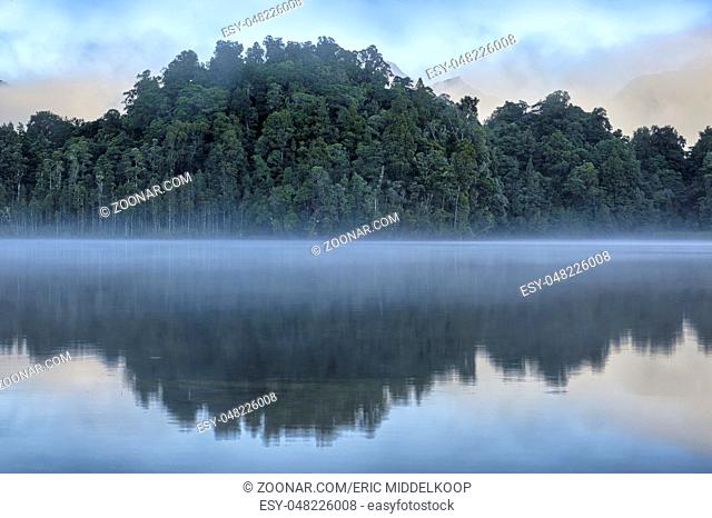 Trees reflected in Lake Kaniere, South Island, New Zealand