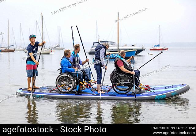 10 September 2023, Schleswig-Holstein, Eckernförde: Participants of the wheelchair SUP event ""Rolli on SUP"" on the Baltic Sea paddle along the shore of Borby