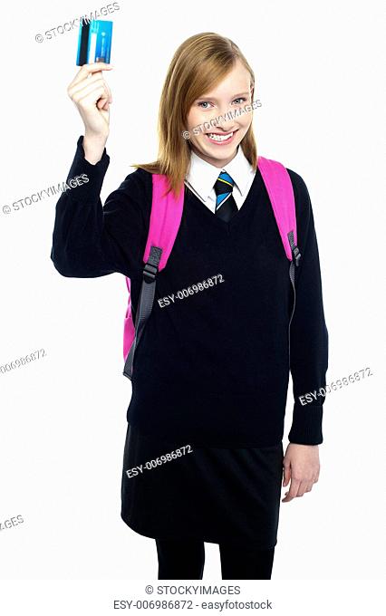 Joyous teen girl in uniform holding up a cash card and showing it to the camera