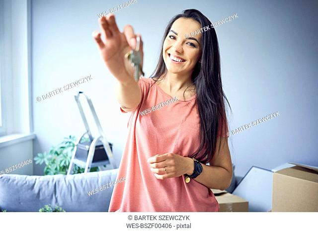 Portrait of happy woman moving in showing keys to new apartment