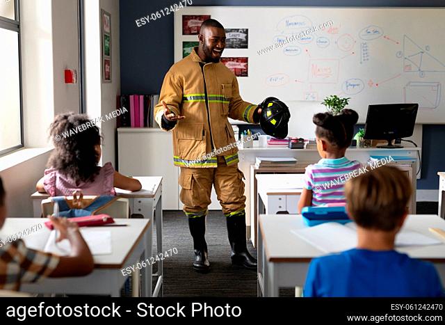 African american young male teacher in firefighter uniform teaching multiracial elementary students