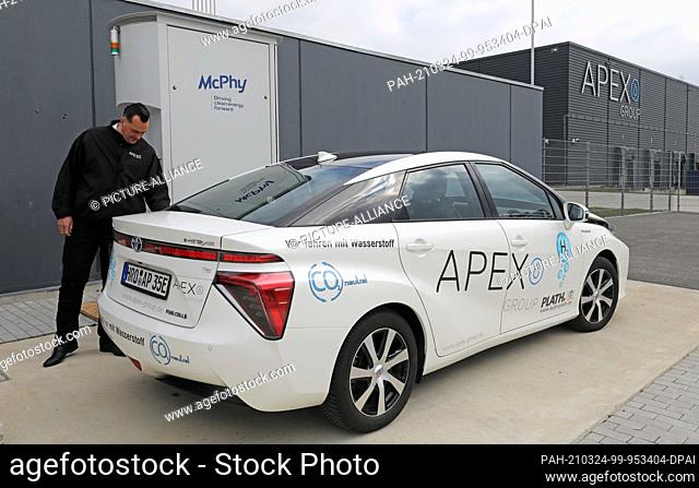 24 March 2021, Mecklenburg-Western Pomerania, Laage: Jörn Hennig, Technical Manager, demonstrates at APEX Energy Teterow GmbH the refuelling of an electric car...
