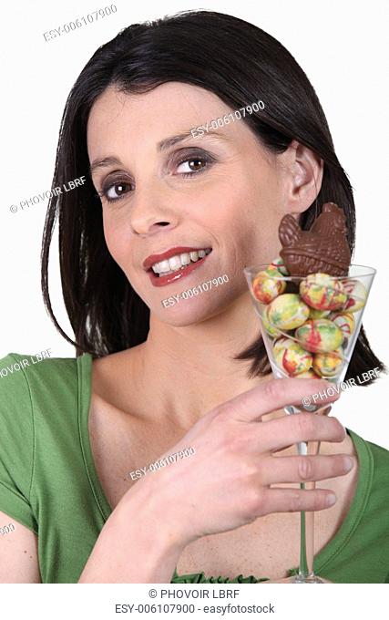 woman holding a glass with Easter chocolate eggs