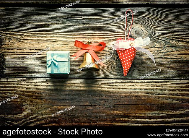New Year. New Year's symbols: a Christmas bell, a self-made heart and a gift box on a wooden background. Copy space, card
