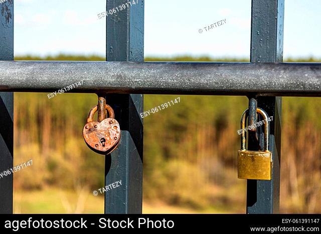 Closeup view of heart-shaped love padlock hanging on a bridge fence