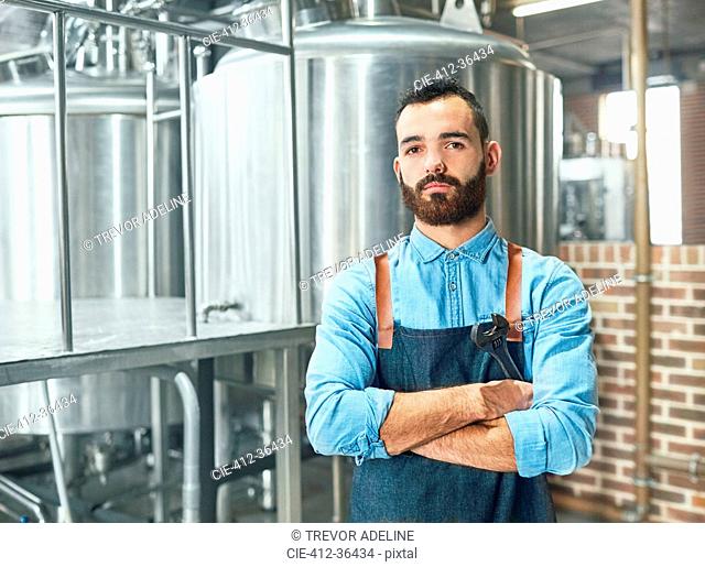 Portrait confident male brewer in front of vat in brewery