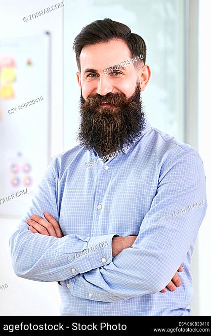 Portrait of a happy bearded senior developer or manager in modern IT office