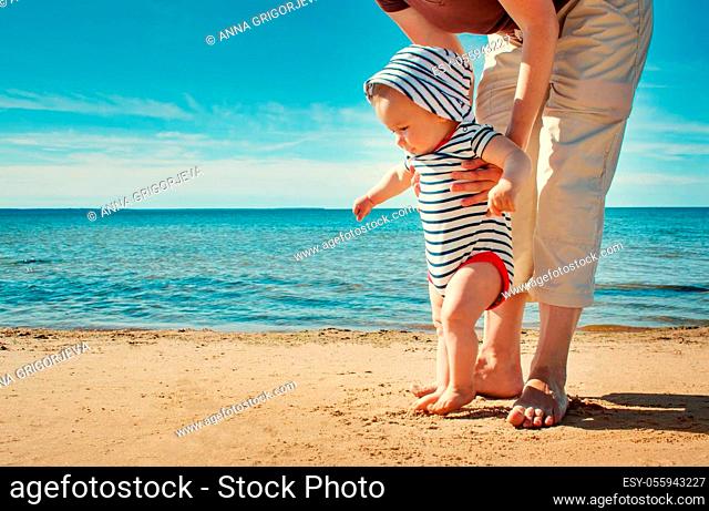 Nine month old baby boy walking on the beach in beautiful summer day