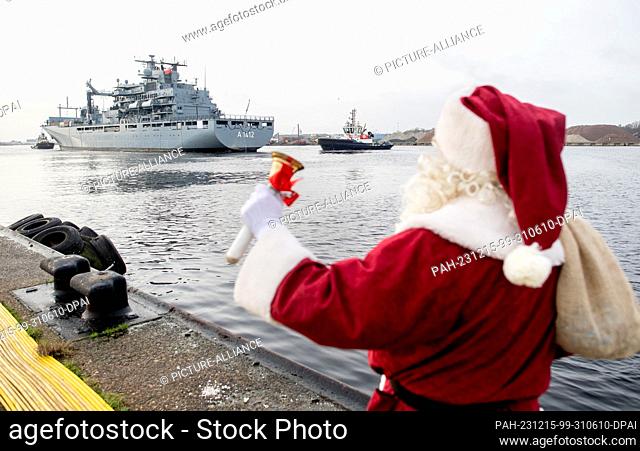 15 December 2023, Lower Saxony, Wilhelmshaven: A marine dressed as Santa Claus waves to the crew as the task force supply ship ""Frankfurt am Main"" enters the...