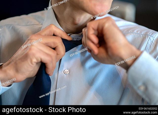 Businessman. A businessman in a blue shirt untieing his tie