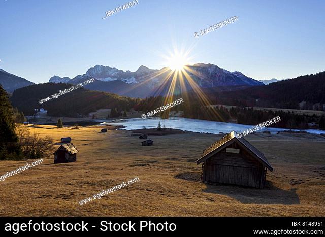 Sunrise over Karwendel mountain range with frozen lake and hay barn, Stadel, Lake Geroldsee, Wagenbruechsee, Gerold, Kruen, Krun, Upper Bavaria, Bavaria
