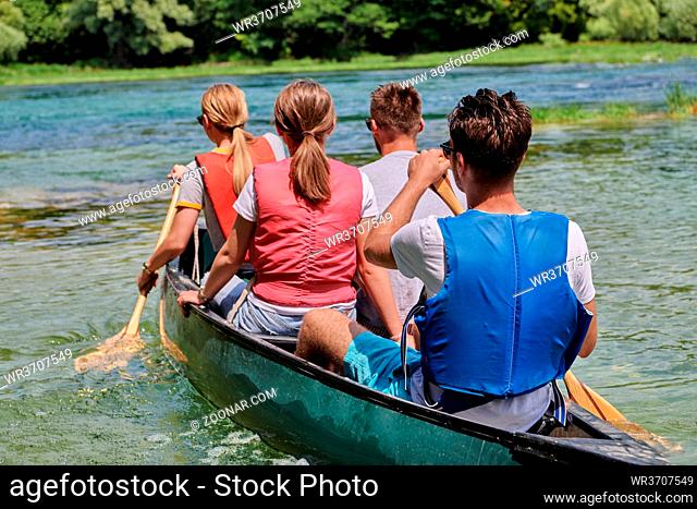 Group adventurous explorer friends are canoeing in a wild river surrounded by the beautiful nature
