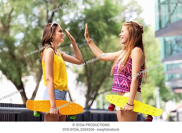 teenage girls with skateboards making high five