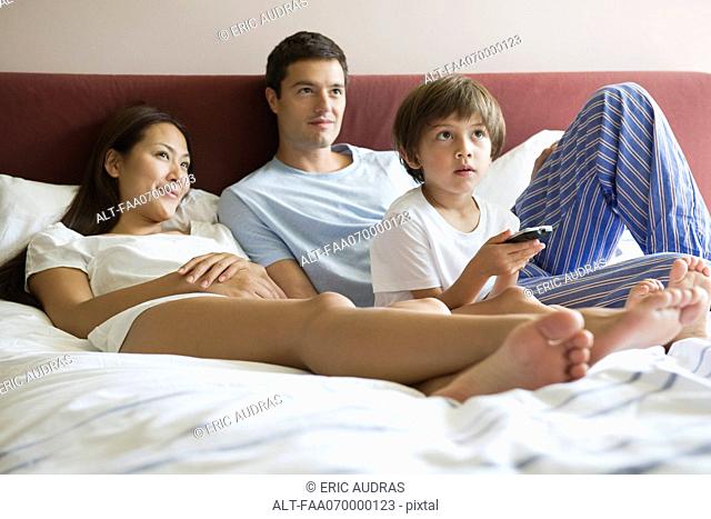 Family watching TV in bed