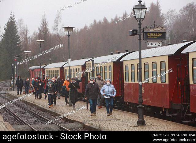 30 December 2021, Saxony-Anhalt, Schierke: Passengers of the Harz narrow gauge railway stand on the platform. In rainy weather and many Harz visitors use the...